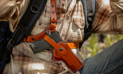 A man with a gun holstred in a chest rig.