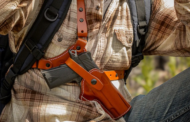 A man with a gun holstred in a chest rig.