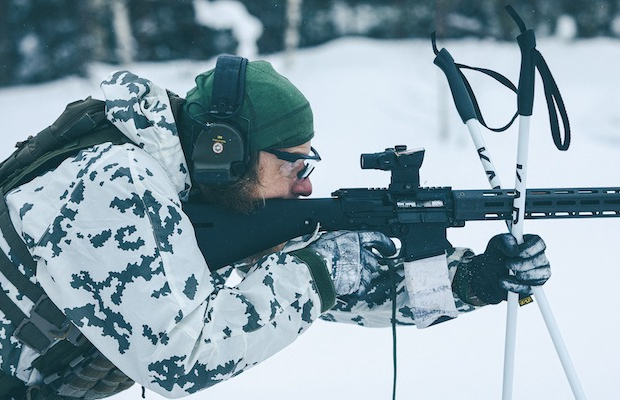 Man shooting a rifle in the snow.