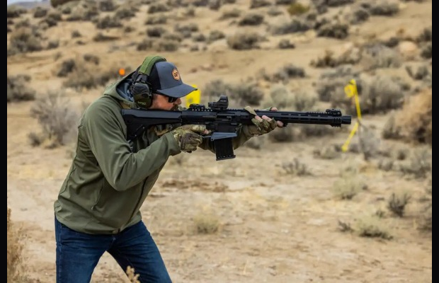 A man shooting a shotgun.