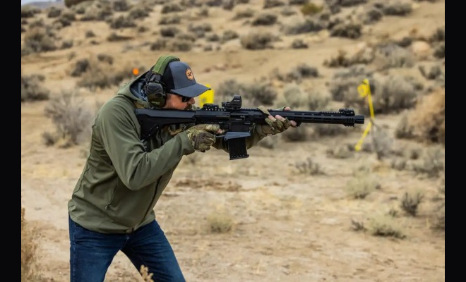 A man shooting a shotgun.