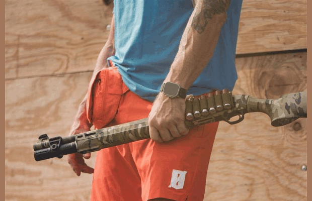 A man in shorts holding a rifle.