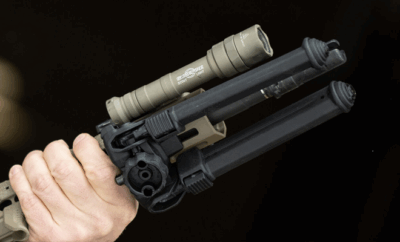 A man hold ing a rifle with a bipod.